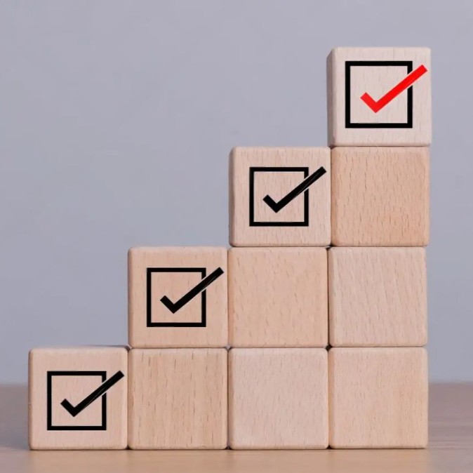Wooden building blocks stacked like stairs, with tick boxes at the top