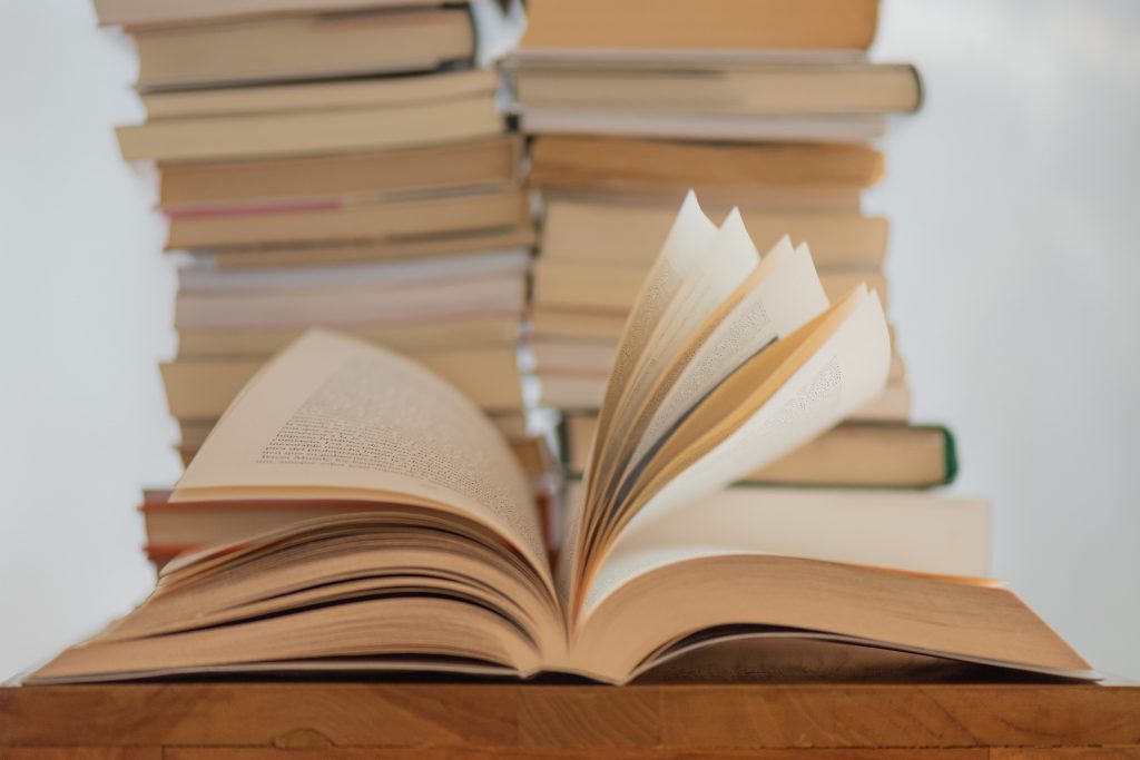 Books piled on a table with one open