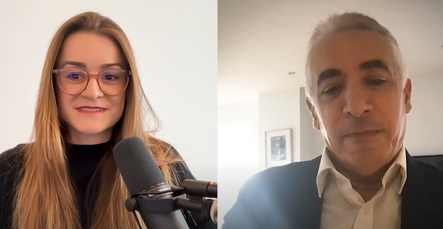 Two people on a video call, one woman with glasses and a microphone, and one man in a suit.