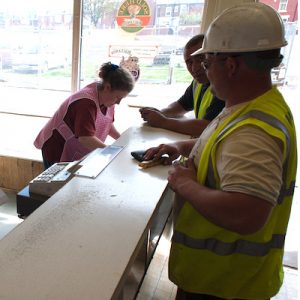 Men in builders uniform conversing with a woman who works at the chippy