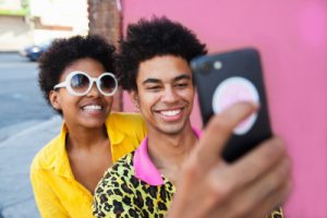 Two people engaging with a mobile phone. These people who would be seen as belonging to a minorities ethnicity in a UK context.