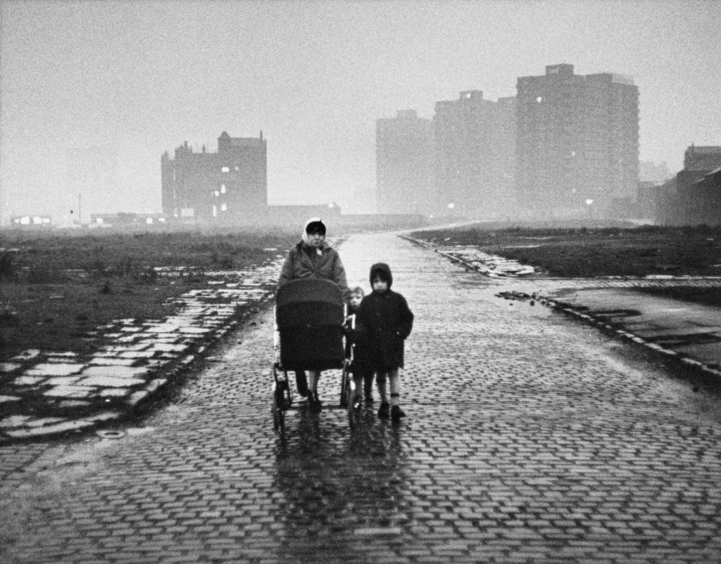 Mother and children walk along deserted cobbled street